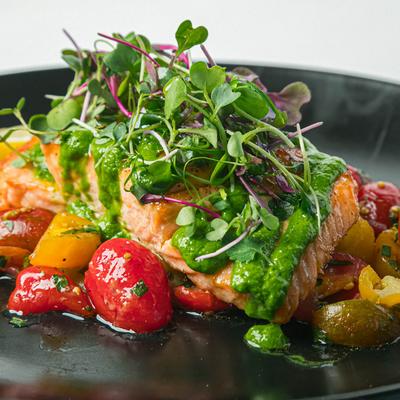 Grilled Scottish salmon fillet, with cherry tomatoes, basil sauce, and microgreens.