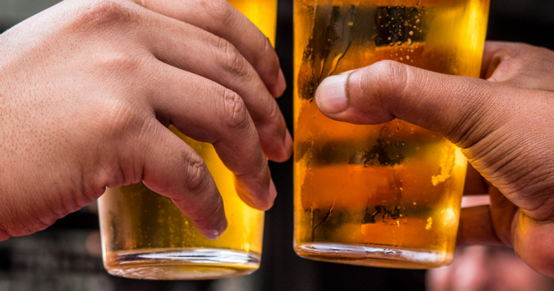 Closeup of guest's hands while making a toast with beer
