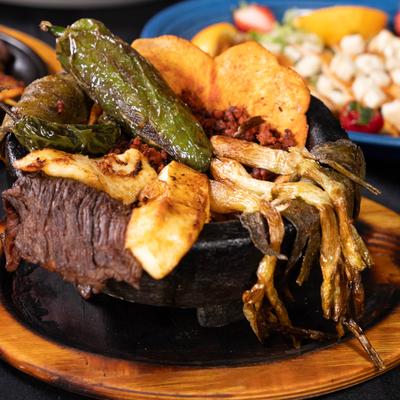 Molcajete with a combination of grilled steak, chicken, chorizo and vegetables.