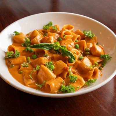 Rigatoni pasta in creamy tomato sauce with peas and herbs.
