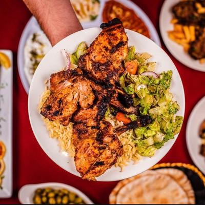 A hand holding the grilled chicken chops plate.