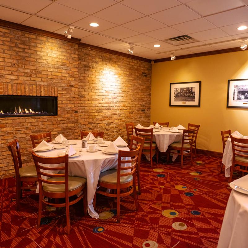 A dining room with brick wall, set round tables, patterned carpet flooring