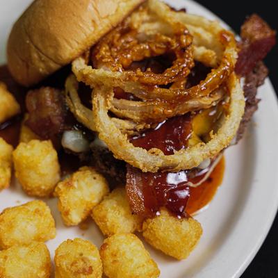 Bacon cheeseburger with onion rings, honey chipotle BBQ sauce, and a side of tots.