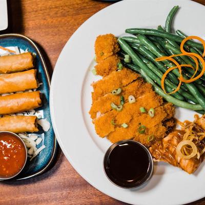 Spring roll plate and crispy fried pork served with green beans and sauce.