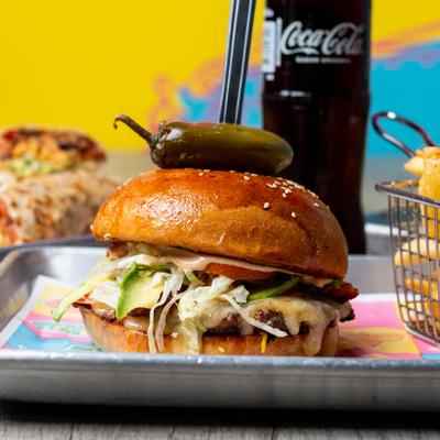 Burger topped with jalapeno beside chips.