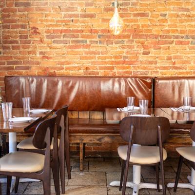 Interior featuring a distinctive rustic brick wall and leather banquette seating.