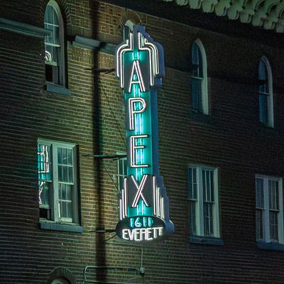 Neon Apex sign on a brick building at night.