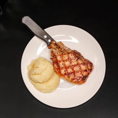 Grilled pork chop served with mashed potatoes.