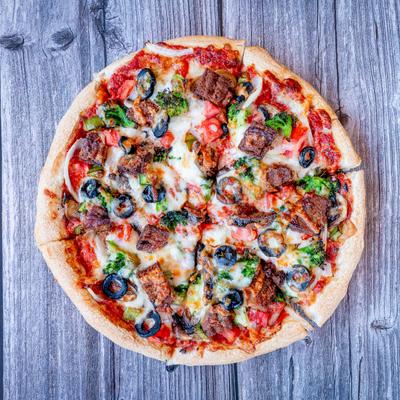 A Veggie Pizza sits on a rustic wooden table.