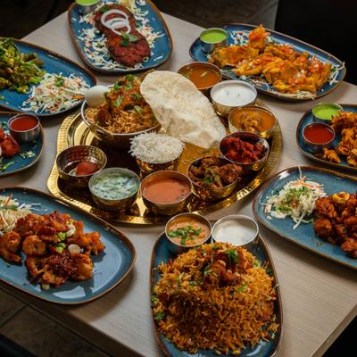 Indian feast with biryani thali, curries, papadum, fried appetizers, and sides.