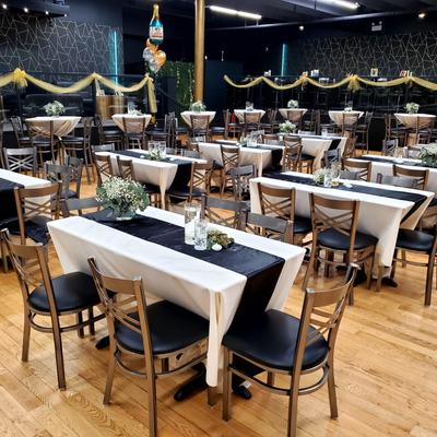 Event space with tables dressed in white tablecloths and black runners.
