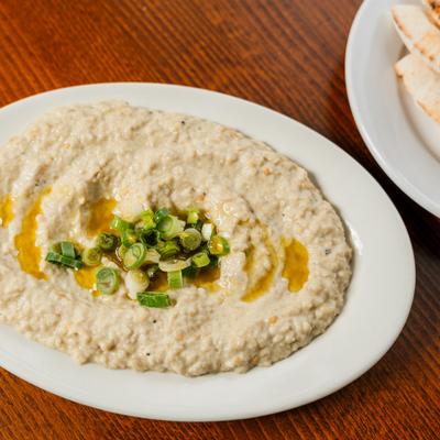 Hummus topped with scallions and olive oil, served with pita bread.
