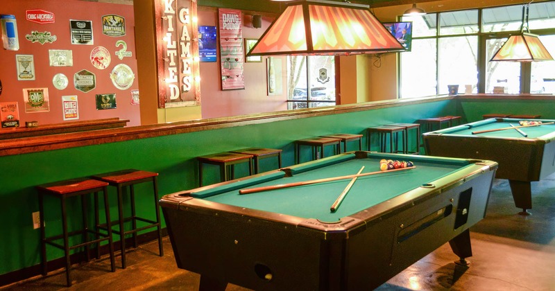 Pool table with bar stools in the back, a wall with images