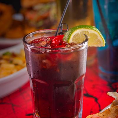 Iced drink garnished with a cherry and a slice of lime.
