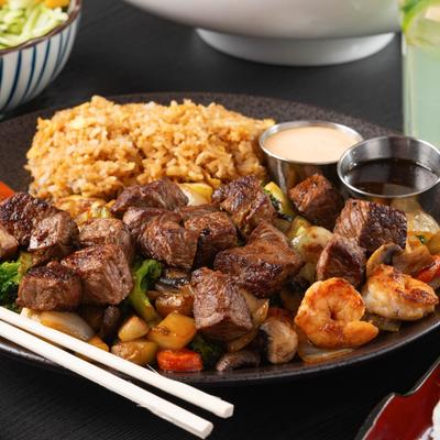 Hibachi steak and shrimp with rice, grilled vegetables, and sauces.