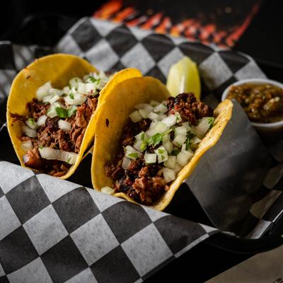 Tow brisket tacos topped with onion and cilantro.