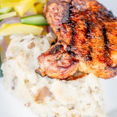 Cajun pork chop served with mashed potatoes and a salad.