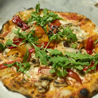A gourmet pizza topped with fresh arugula, mushrooms, and vegetables.