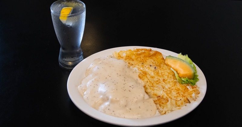 Biscuits Gravy served with hashbrowns and a melon wedge, accompanied with a beverage