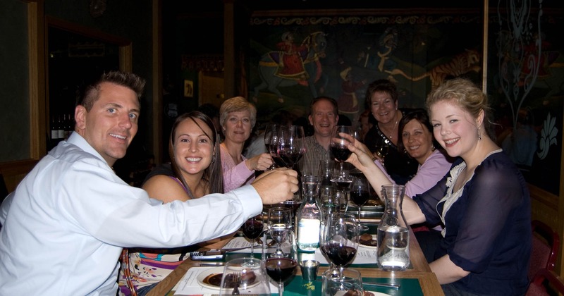 Group of jolly guests looking at the camera and making toast with wine