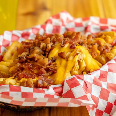 Loaded Fries in a basket lined with a red and white checkered paper.