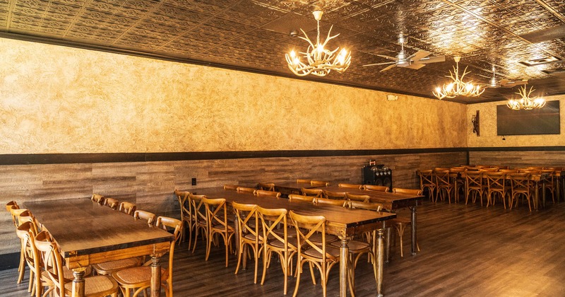 Interior, long tables with chairs, pendant lights, ceiling fan, mounted TV