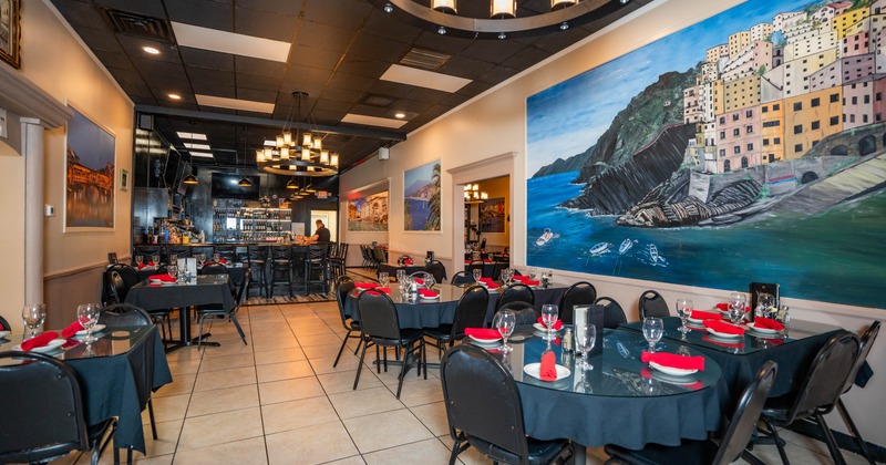 Restaurant interior with tables, black tablecloths and a bar area