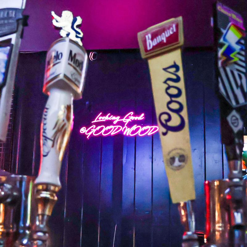 Beer taps with neon Goodwood sign in the background.