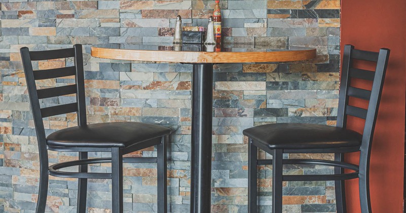 Interior, a table for two by a natural stone wall
