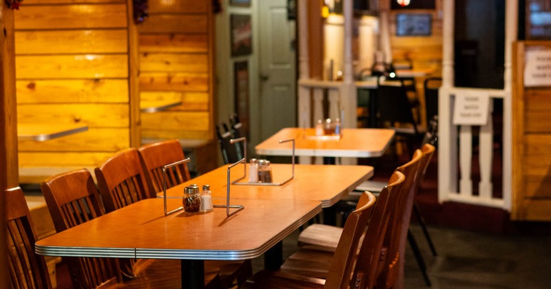 Interior of a restaurant with wooden tables and chairs, warm lighting, and festive decor