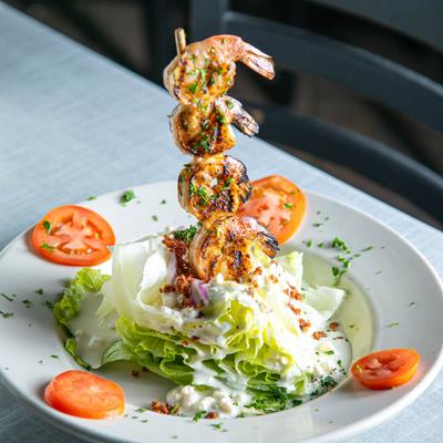 The Bleu Wedge salad served with a grilled shrimp skewer.