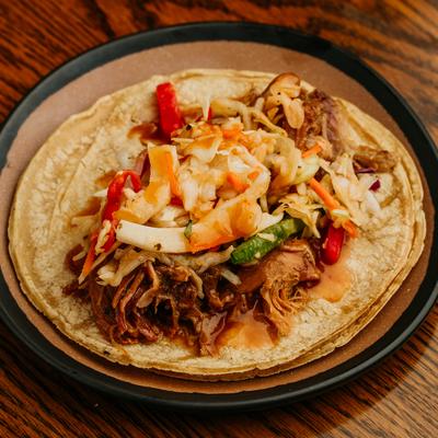 Open-faced pulled pork taco with coleslaw and red peppers.