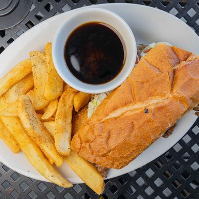Ribeye sandwich with a side of au jus and thick-cut fries.