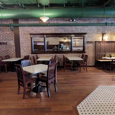 Interior with brick walls, wooden tables and chairs, and booths.
