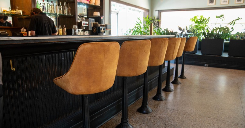 Bar counter seating, upholstered stools lined up along the bar counter