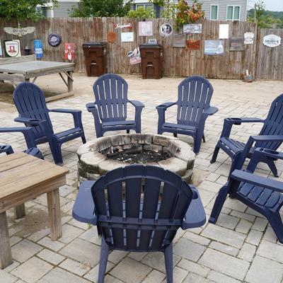 Outdoors, adirondack chairs around a fire pit.