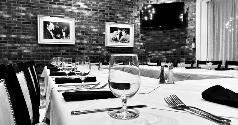 A long, elegantly set table featuring white linens, glassware, and cutlery