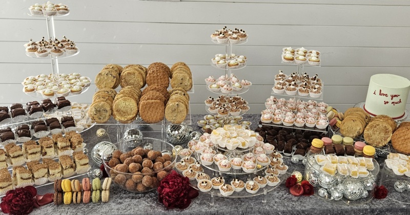 A wide picture of the various different products available at the sweet shop such as candy, cupcakes, cakes, and brownies