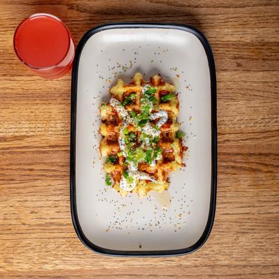 Savory waffle with cream cheese and scallions served with a glass of juice.