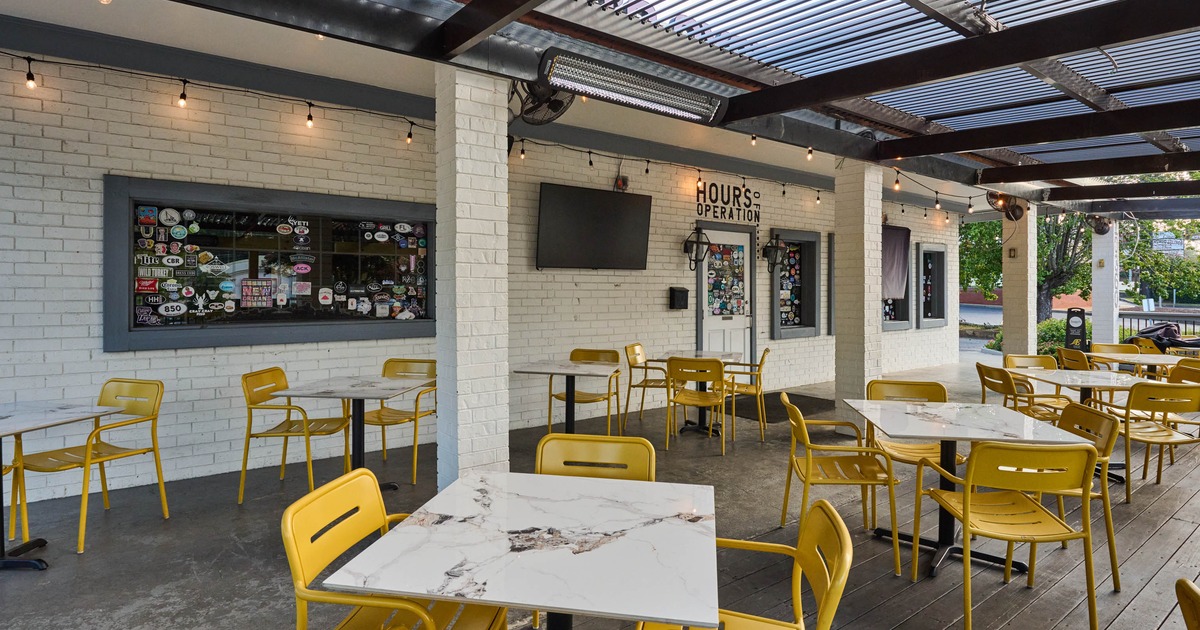 Outdoor seating area with yellow chairs and white tables