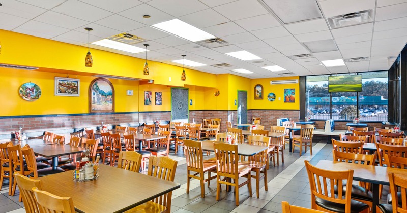 Interior, open space seating area, wooden top tables with wooden chairs, tile flooring