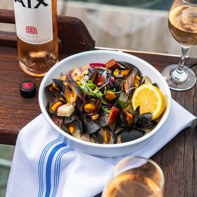 Seafood appetizer consisting of steamed mussels served in a broth, paired with rose wine.
