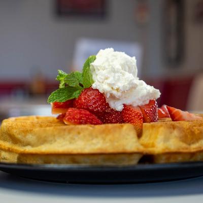 Belgian waffle topped with strawberries and whipped cream.