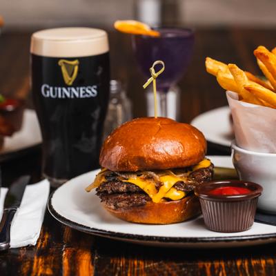 Double cheeseburger served with fries, ketchup, and a pint of stout.