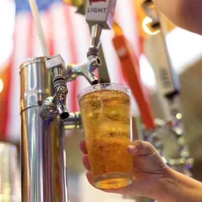 A hand holding a glass of beer under the dispensary.
