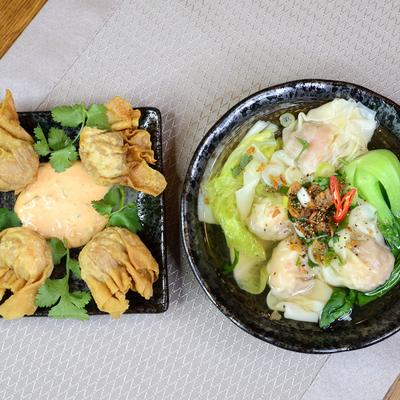 A plate of crispy wontons with sauce next a bowl of dumplings.