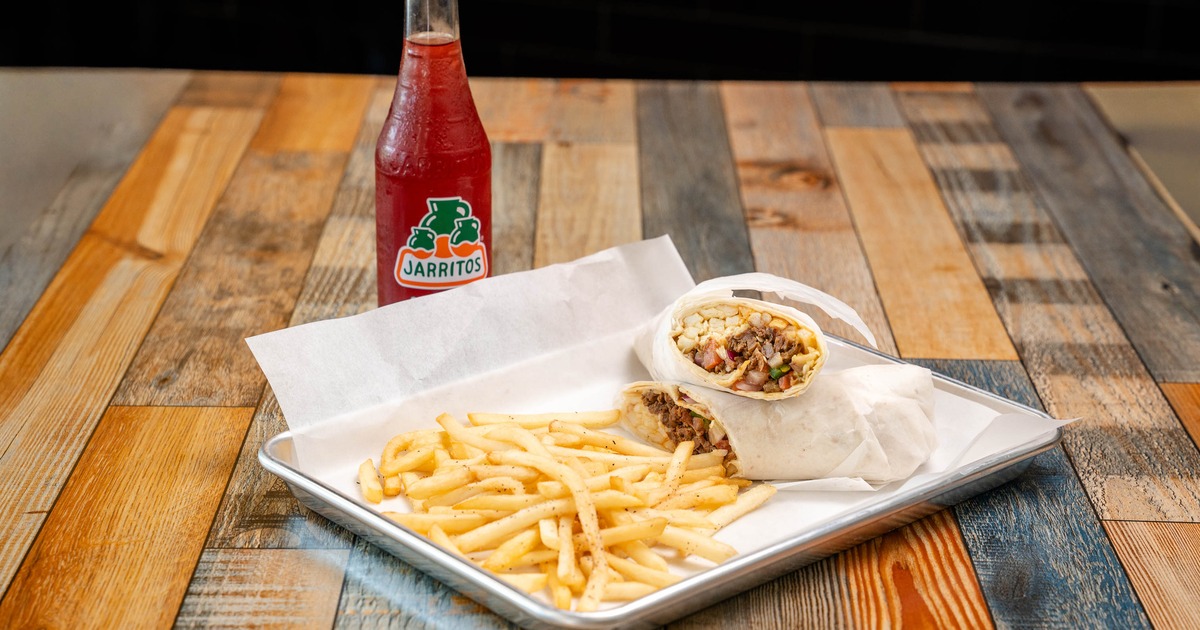 Burrito served on a tray with fries and a bottle of soda