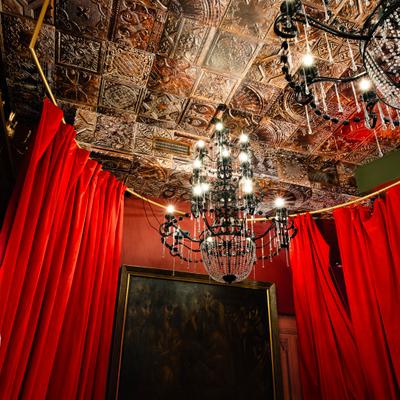 Chandeliers and ceiling decoration above red curtains.
