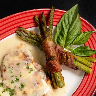 Chicken Saltimbocca served with bacon wrapped asparagus , garnished with fresh basil.
