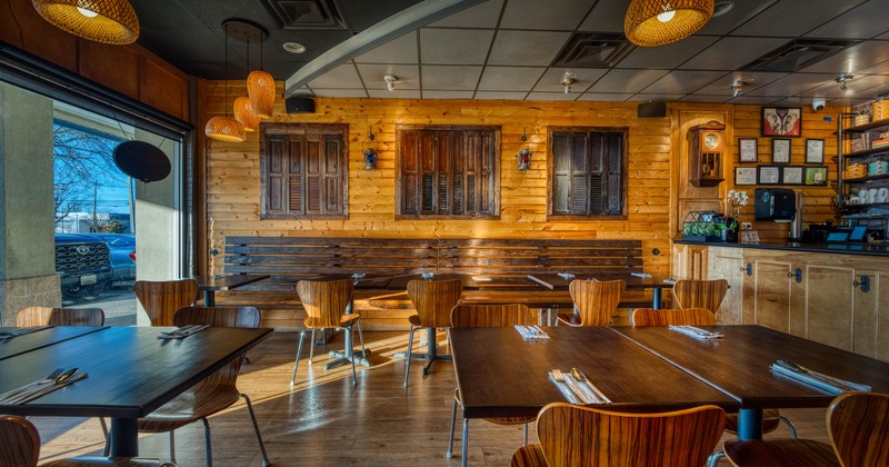 A rustic restaurant interior with wooden furniture, and natural light from large windows